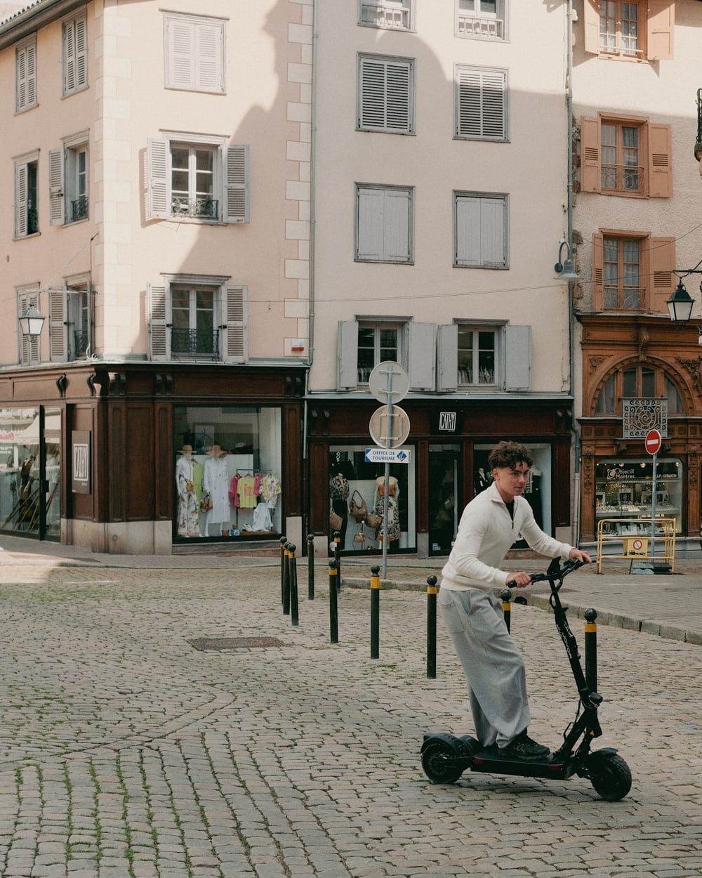 Rider on an electric scooter crossing a cobblestone town square